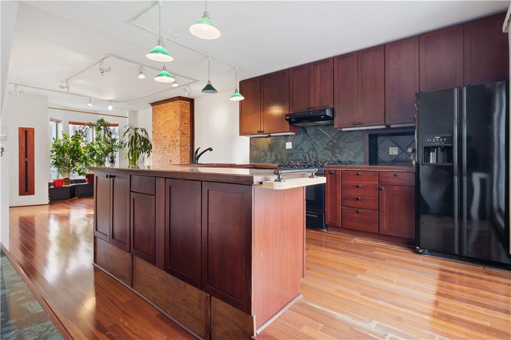 457 44th Street Brooklyn, NY 11220 - Photo 6 of 16 a kitchen with stainless steel appliances granite countertop a refrigerator a sink dishwasher and wooden cabinets with wooden floor
