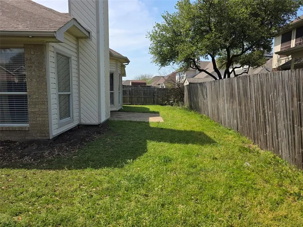a view of backyard with wooden fence and large trees