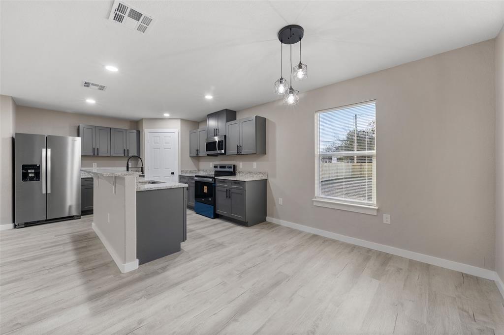 1905 Sanger Avenue Waco, TX 76707 - Photo 7 of 21 a large kitchen with stainless steel appliances granite countertop a stove top oven a refrigerator a sink and a dining table with wooden floor