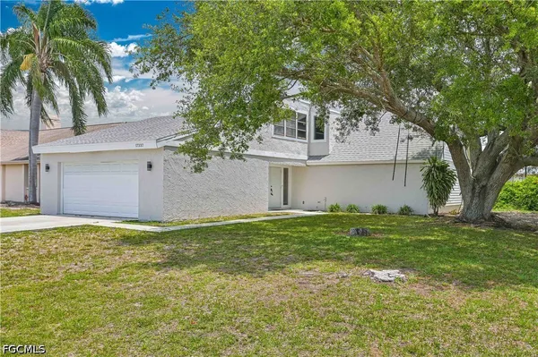 a view of a house with a yard and a large tree