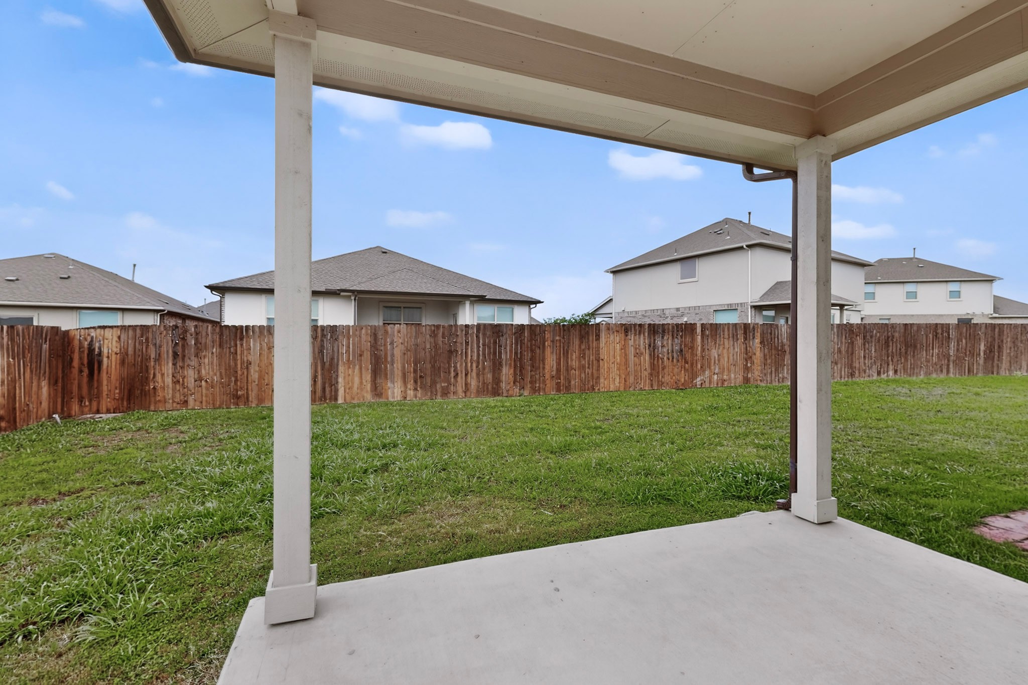 16809 Guido Cove Pflugerville, TX 78660 - Photo 34 of 40 Concrete patio area featuring a covered porch structure, a wood privacy fence, and a grass lawn