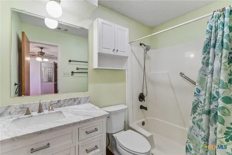 a bathroom with a granite countertop sink toilet and shower