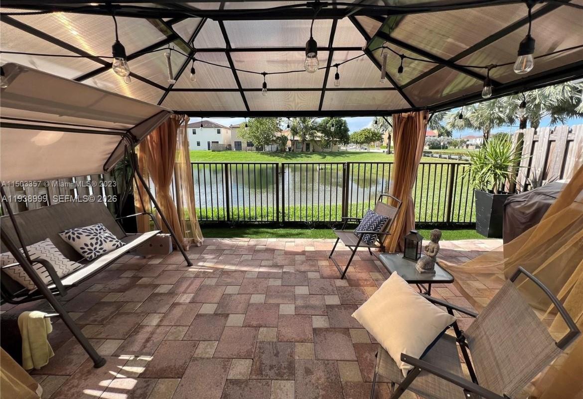 23218 Southwest 113 Passage Homestead, FL 33032 - Photo 21 of 23 a view of a patio with table and chairs under an umbrella with a small yard