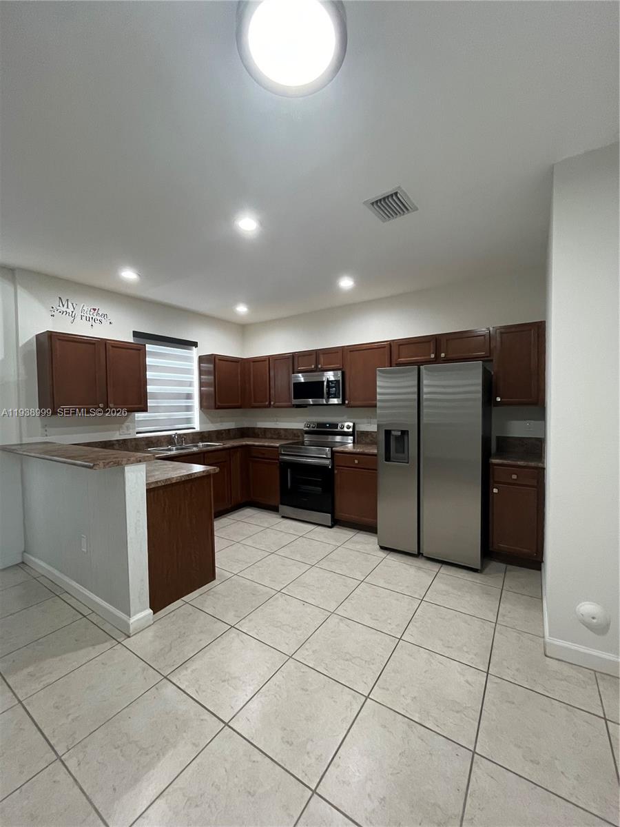 23218 Southwest 113 Passage Homestead, FL 33032 - Photo 5 of 23 a kitchen with stainless steel appliances granite countertop a refrigerator and a sink