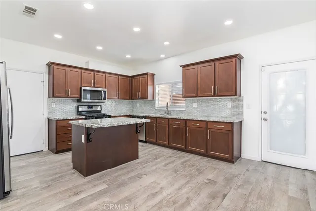 a large kitchen with kitchen island granite countertop wooden cabinets a stove a sink and dishwasher