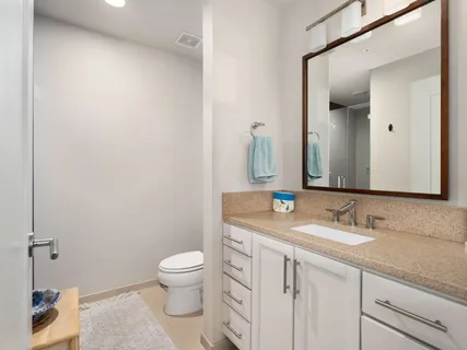 a bathroom with a granite countertop sink a toilet and a mirror