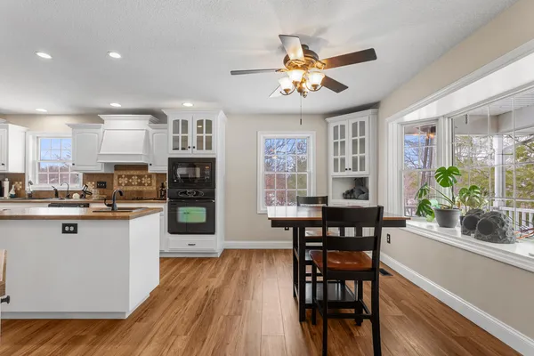 a kitchen with stainless steel appliances granite countertop a dining table chairs refrigerator and sink