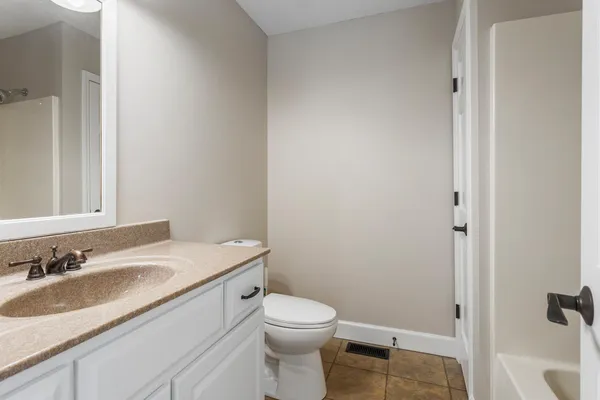 a bathroom with a granite countertop sink toilet and a mirror