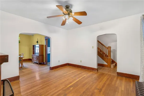 a view of an empty room with wooden floor and a ceiling fan