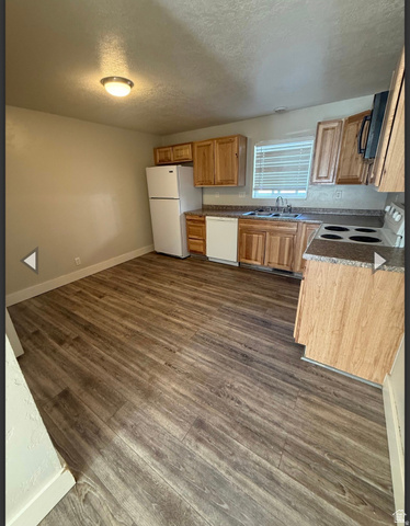 106 East Richelman Lane Wellington, UT 84542 - Photo 5 of 35 Kitchen with a textured ceiling, white appliances, dark wood-style floors, and wood finish cabinetry