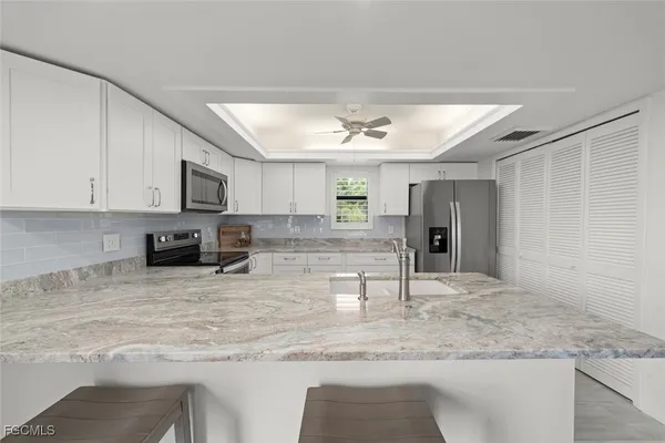 a view of a kitchen with kitchen island a sink stainless steel appliances and a counter top space