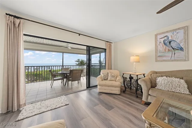 a living room with furniture large windows and wooden floor