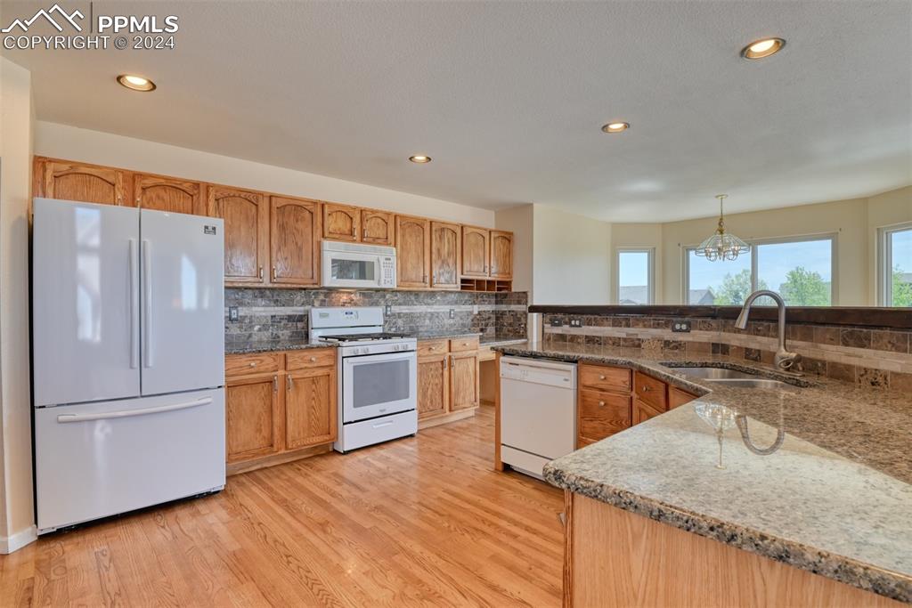 7863 Buschborn Road Peyton, CO 80831 - Photo 5 of 50 a kitchen with granite countertop wooden floors stainless steel appliances and a counter
