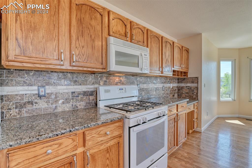 7863 Buschborn Road Peyton, CO 80831 - Photo 7 of 50 a kitchen with granite countertop a stove a sink dishwasher and cabinets with wooden floor
