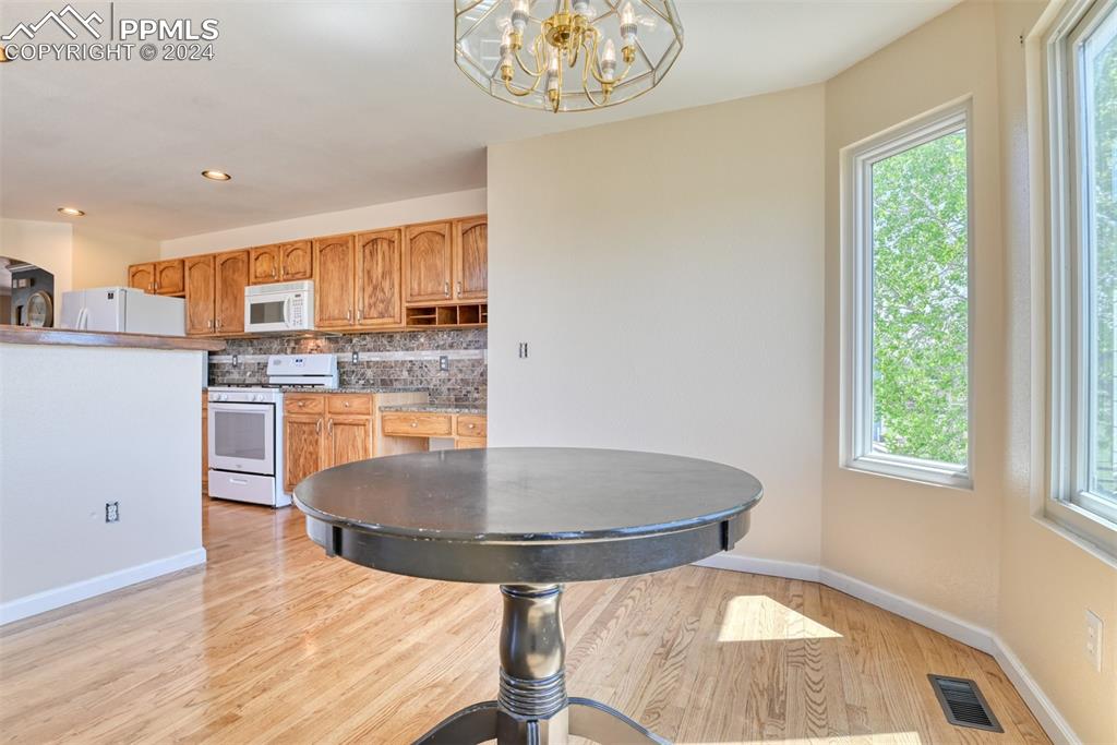 7863 Buschborn Road Peyton, CO 80831 - Photo 9 of 50 a kitchen with stainless steel appliances granite countertop a stove a refrigerator a microwave oven with a dining table and chairs
