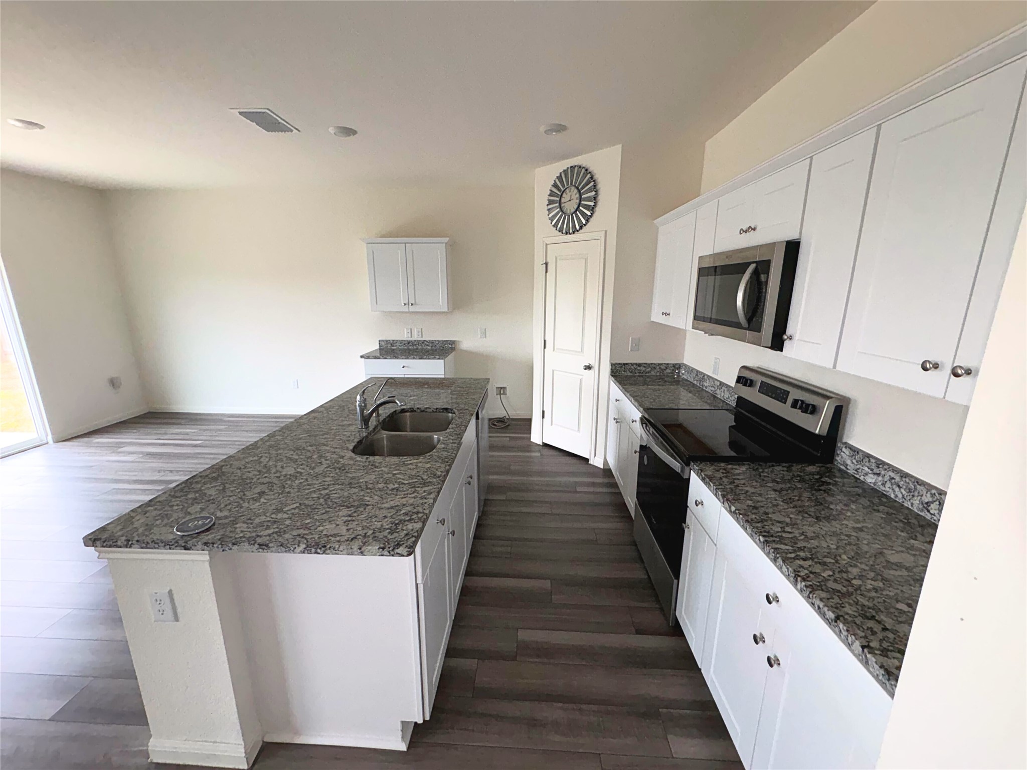 410 Magnum Force Drive Jarrell, TX 76537 - Photo 4 of 18 Kitchen featuring appliances with stainless steel finishes, white cabinets, an island with sink, dark stone counters, and dark wood-style floors