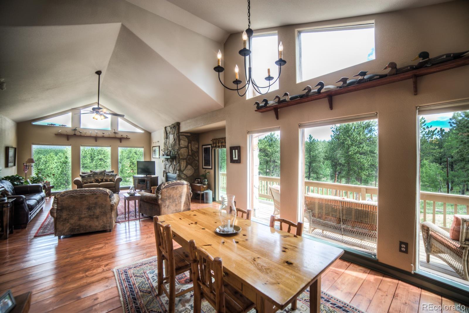 264 Hangmans Road Bailey, CO 80421 - Photo 11 of 33 a view of a dining room with furniture a chandelier and large windows