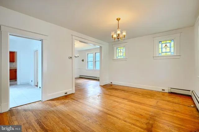 an empty room with wooden floor chandelier and windows