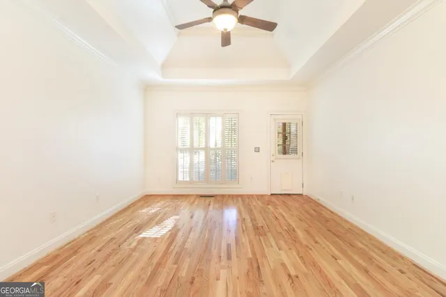 an empty room with wooden floor fan and windows