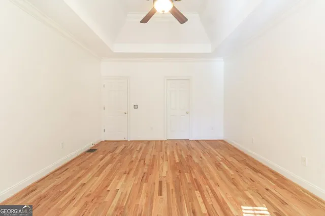 a view of a room with wooden floor and a ceiling fan