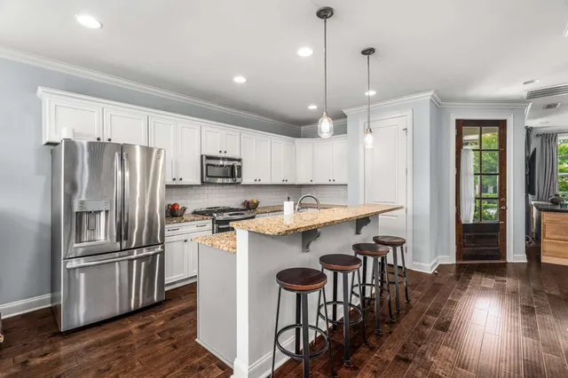 a kitchen with kitchen island granite countertop wooden floor cabinets and stainless steel appliances