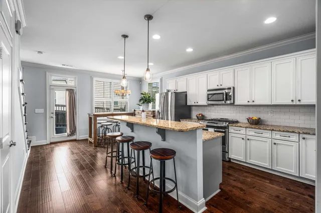 a kitchen with stainless steel appliances granite countertop a stove top oven a sink a refrigerator and cabinets