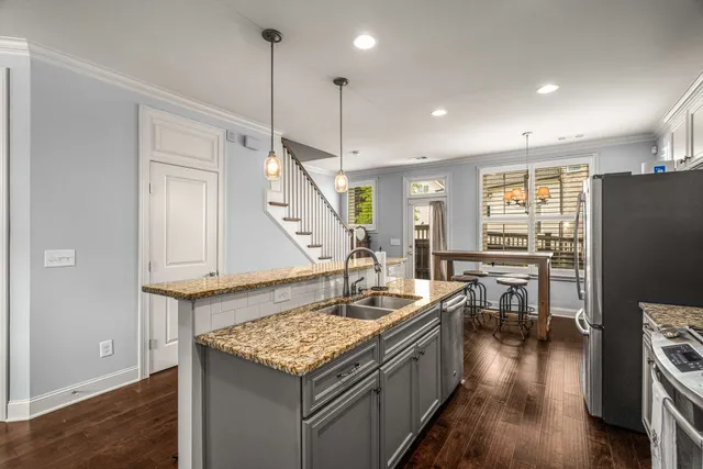 a kitchen with a table chairs refrigerator and wooden floor