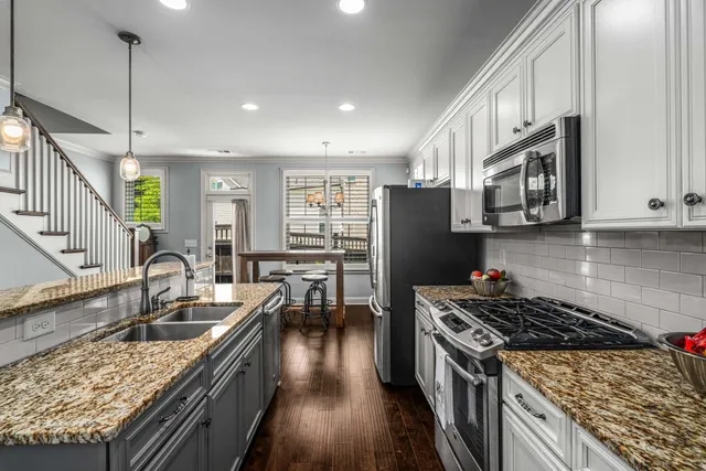 a kitchen with granite countertop a stove a sink a refrigerator and wooden cabinets