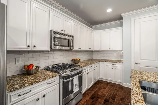 a kitchen with stainless steel appliances granite countertop white cabinets sink and stove