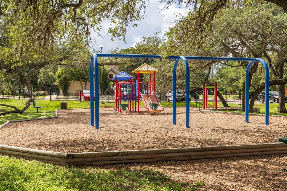 7136 Ridge Oak Road Austin, TX 78749 - Photo 28 of 28 A vibrant playground with a soft, wood chip surface provides an engaging recreational space.