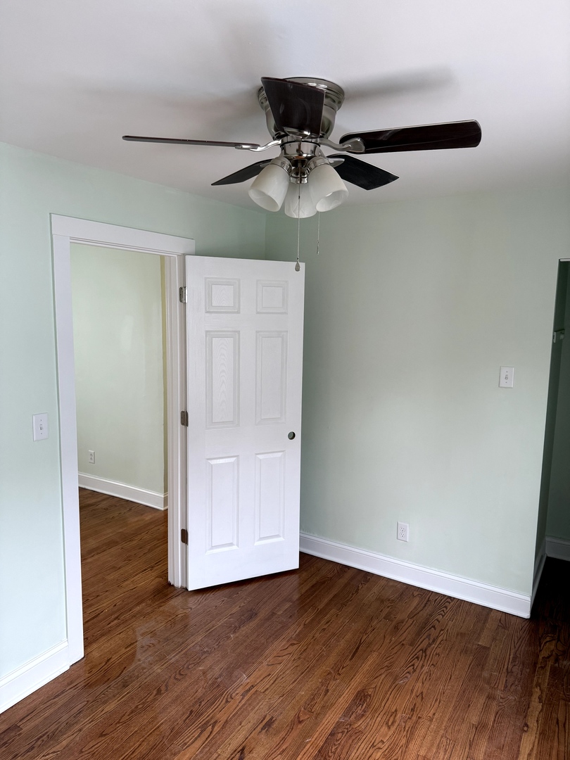 7744 South Champlain Avenue Chicago, IL 60619 - Photo 15 of 21 an empty room with wooden floor fan and windows