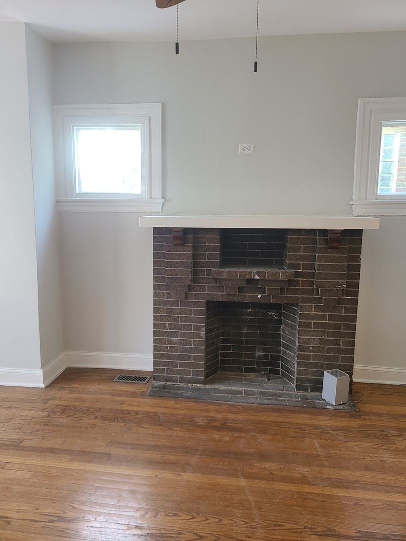 7744 South Champlain Avenue Chicago, IL 60619 - Photo 5 of 21 an empty room with wooden floor and fireplace
