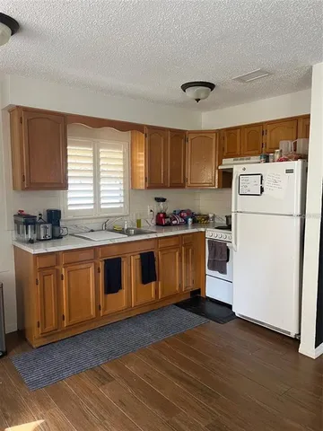 a kitchen with granite countertop wooden floors stainless steel appliances and window