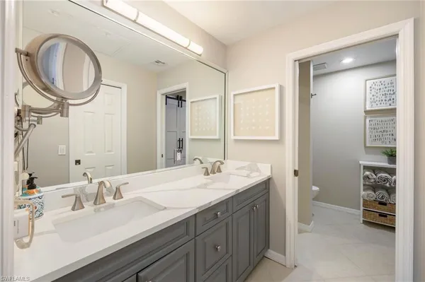a bathroom with a double vanity sink a mirror and a toilet