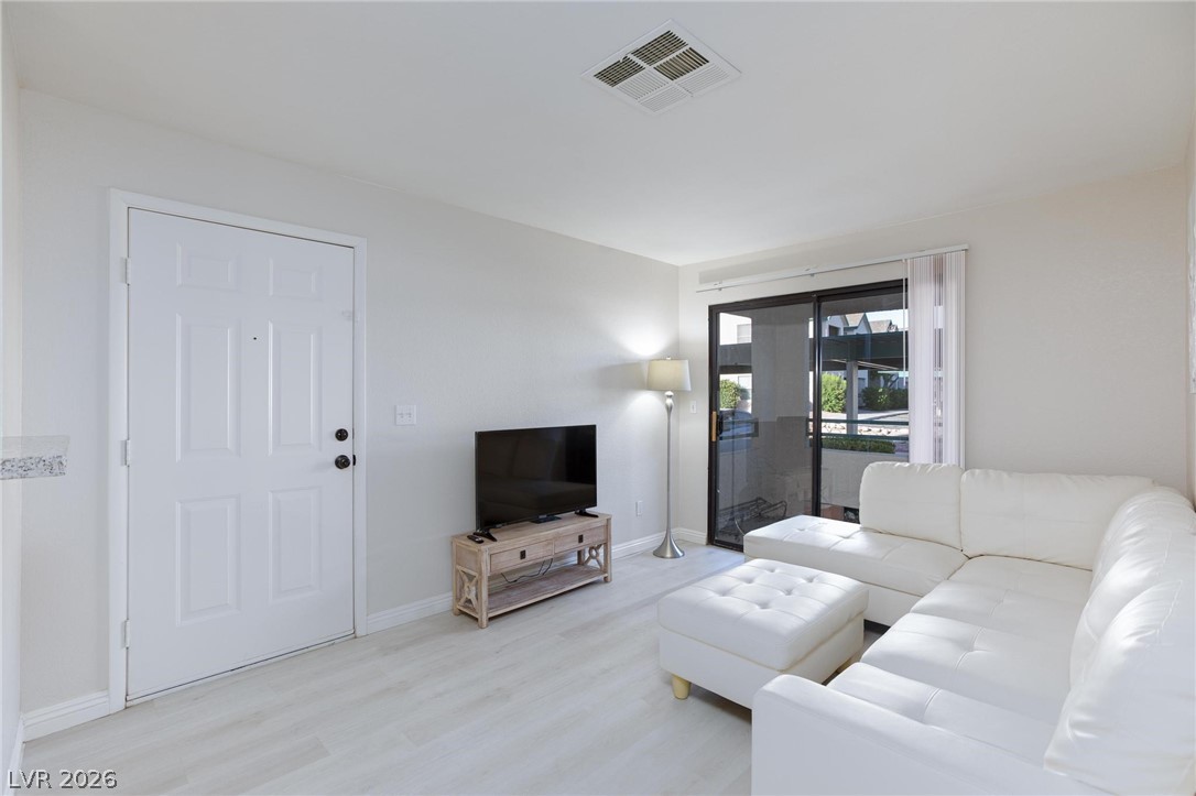 5171 South Lindell Road, Unit 103 Las Vegas, NV 89118 - Photo 5 of 24 A naturally illuminated living area featuring sleek light-toned flooring and seamless outdoor access.
