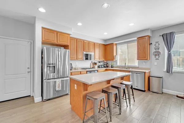 a large kitchen with stainless steel appliances granite countertop a stove a sink a refrigerator and white cabinets with wooden floor