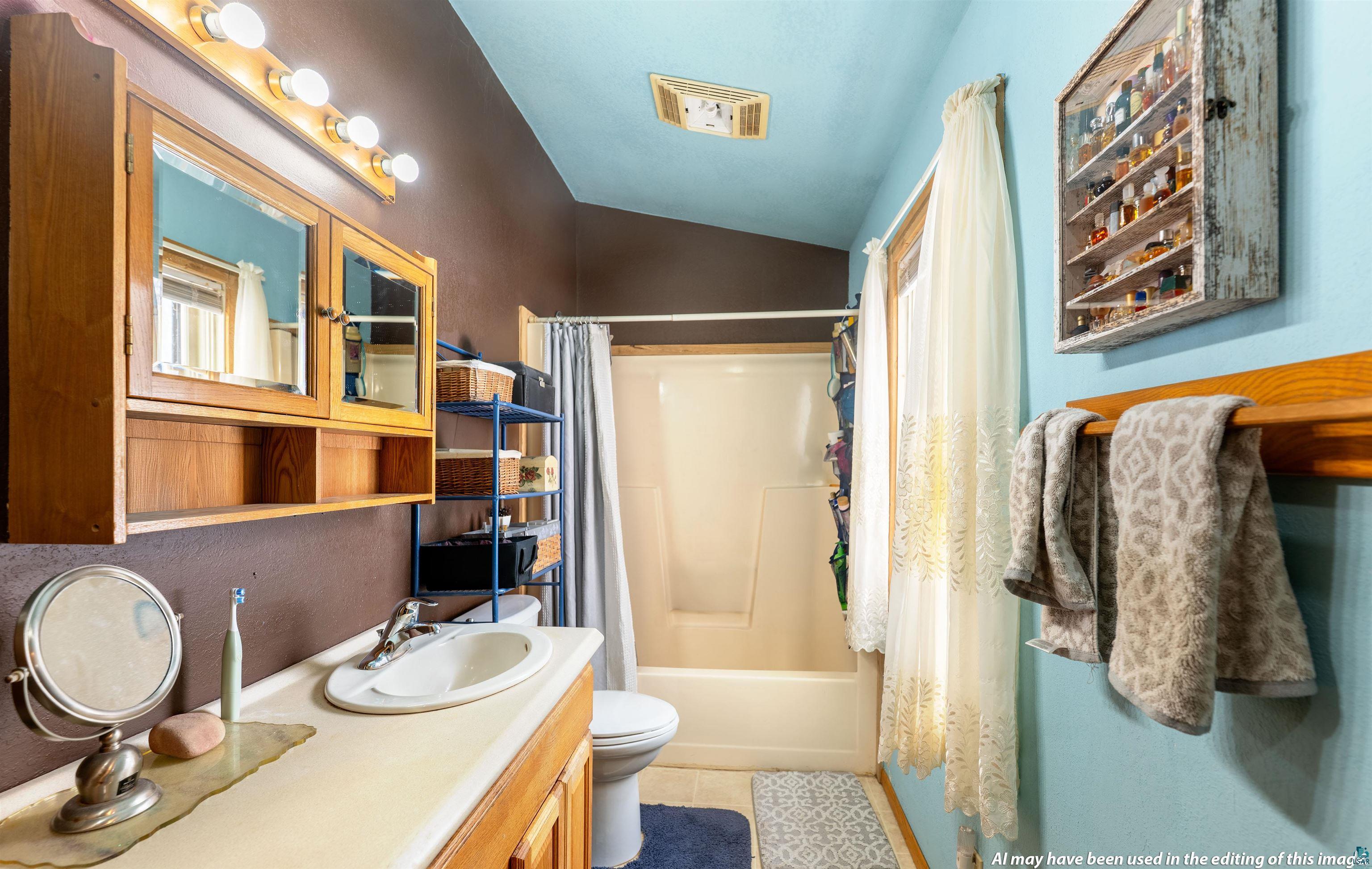 6030 Lake Ahmeek Road Hughes, WI 54847 - Photo 13 of 26 Full bath featuring vanity, shower / bathtub combination with curtain, vaulted ceiling, and light tile patterned flooring