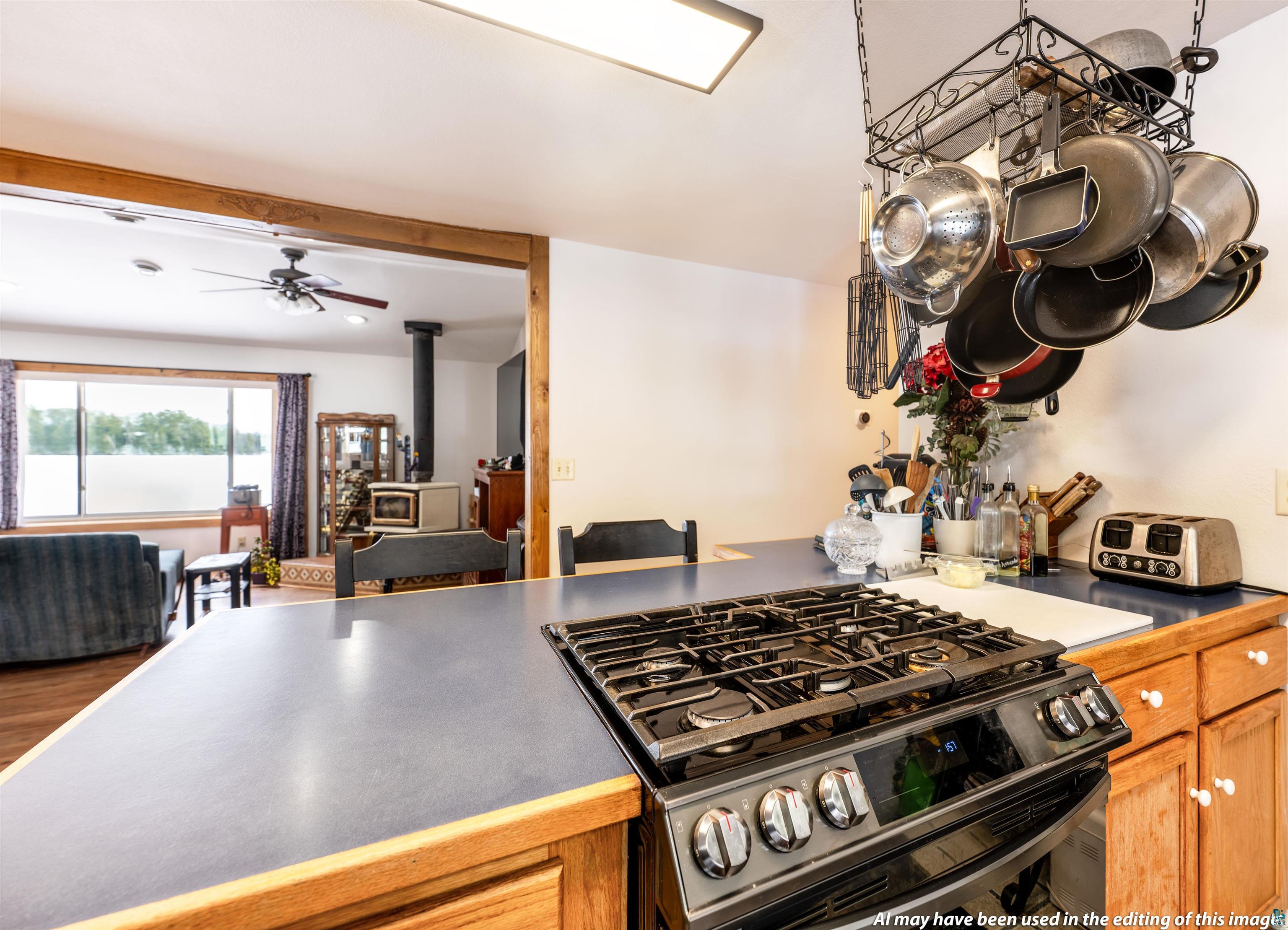 6030 Lake Ahmeek Road Hughes, WI 54847 - Photo 10 of 26 Kitchen featuring gas stove, a wood stove, dark countertops, and a ceiling fan