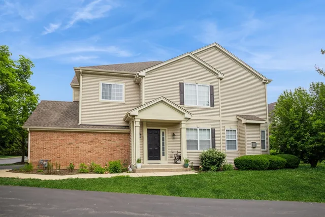 a front view of a house with a yard and tree