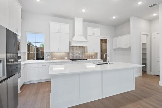 a kitchen with kitchen island white cabinets and stainless steel appliances