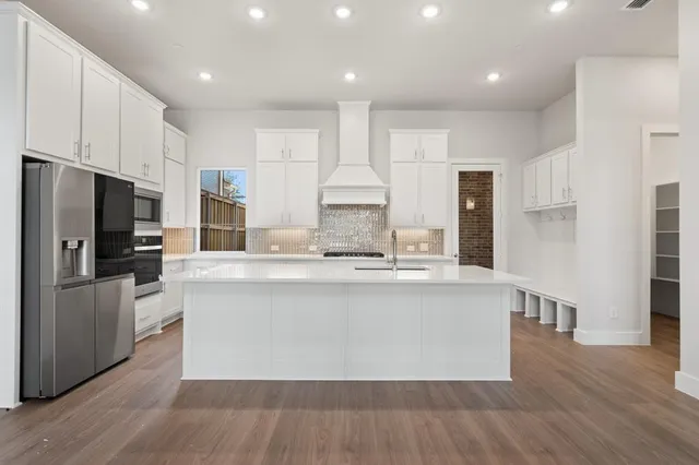 a large kitchen with stainless steel appliances a large counter top a stove a refrigerator and a cabinets