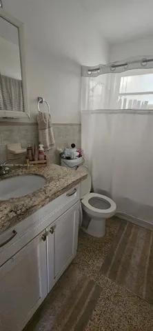 a bathroom with a granite countertop sink a toilet and a mirror