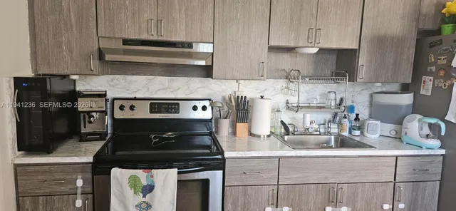 a kitchen with granite countertop a stove and a white cabinets
