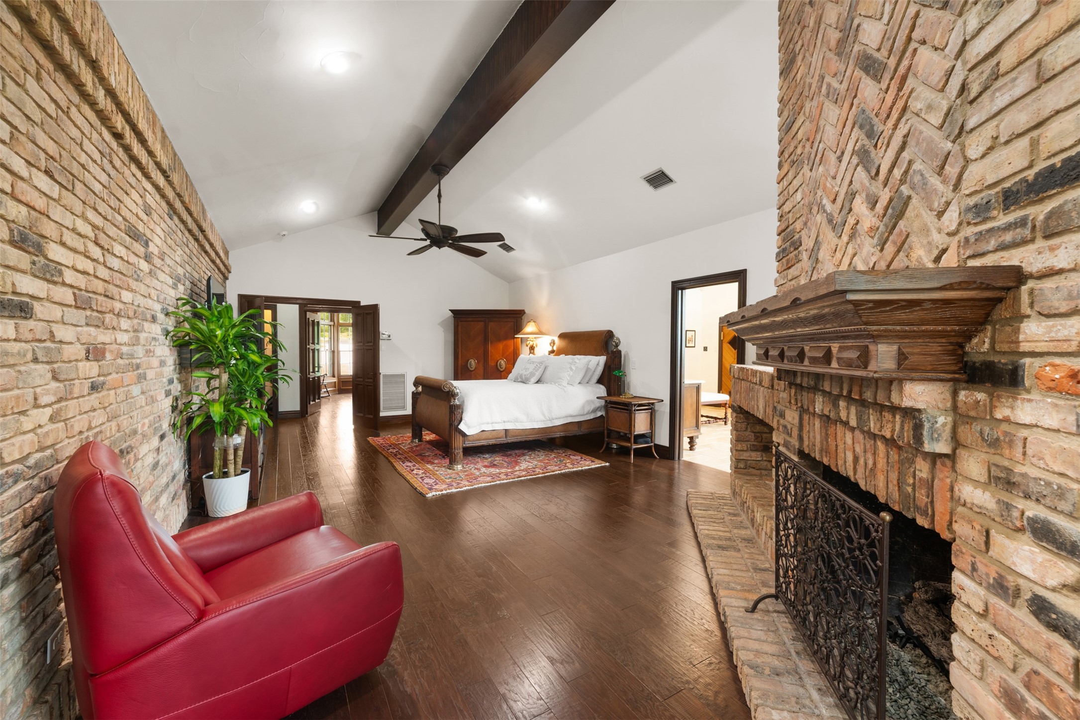 34000 Smithson Valley Road Bulverde, TX 78163 - Photo 18 of 50 A true owner's retreat, the spacious primary suite features rich hardwood flooring, exposed beams, and a dramatic brick fireplace. Warm architectural details and generous proportions create a luxurious yet inviting atmosphere.
