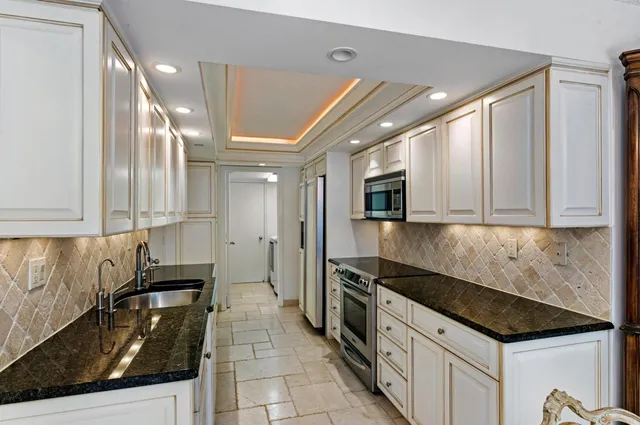 a kitchen with granite countertop a sink stainless steel appliances and cabinets