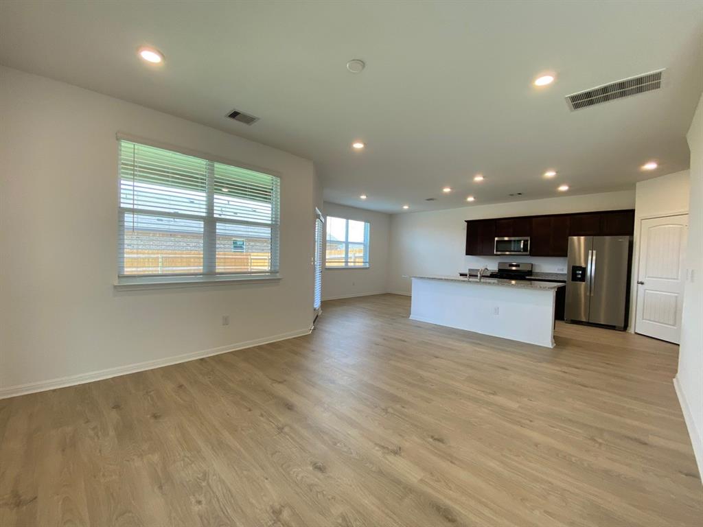 225 Saide Street Georgetown, TX 78626 - Photo 3 of 22 a view of kitchen with kitchen island a sink wooden floor and a refrigerator