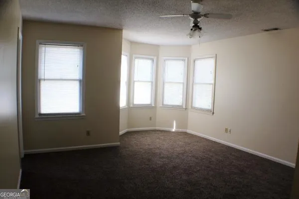 an empty room with windows and chandelier fan