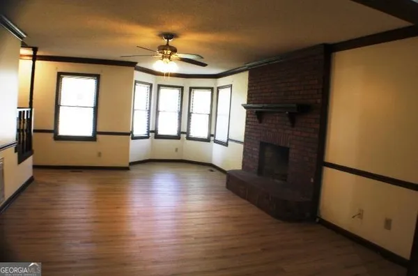 an empty room with wooden floor fireplace and windows