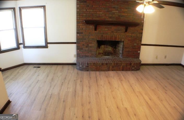 118 Whipoorwill Way Dublin, GA 31021 - Photo 10 of 28 an empty room with wooden floor a fireplace and windows