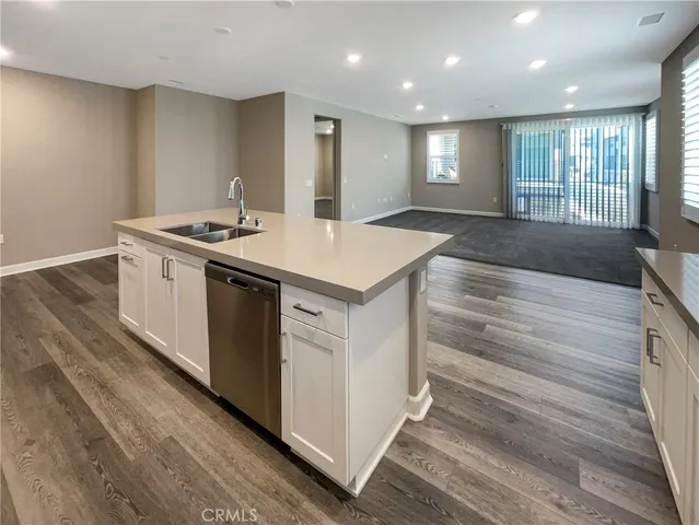 a kitchen with stainless steel appliances granite countertop a refrigerator a sink a stove and white cabinets with wooden floor